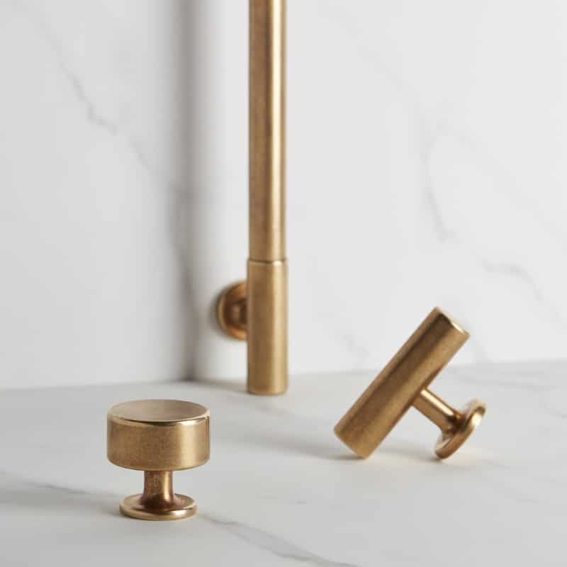 Gold-toned bathroom faucet handles resting on a white marble countertop. The image shows two knobs and a tall spout in a modern fixture.